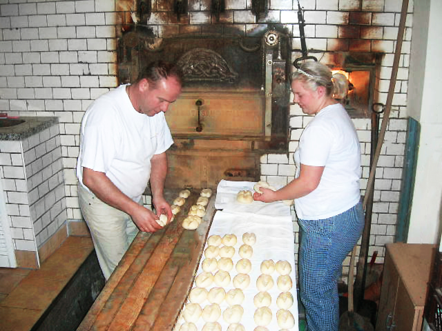 Brötchen werden mit dem Schlagschieber in den Steinbackofen geschoben